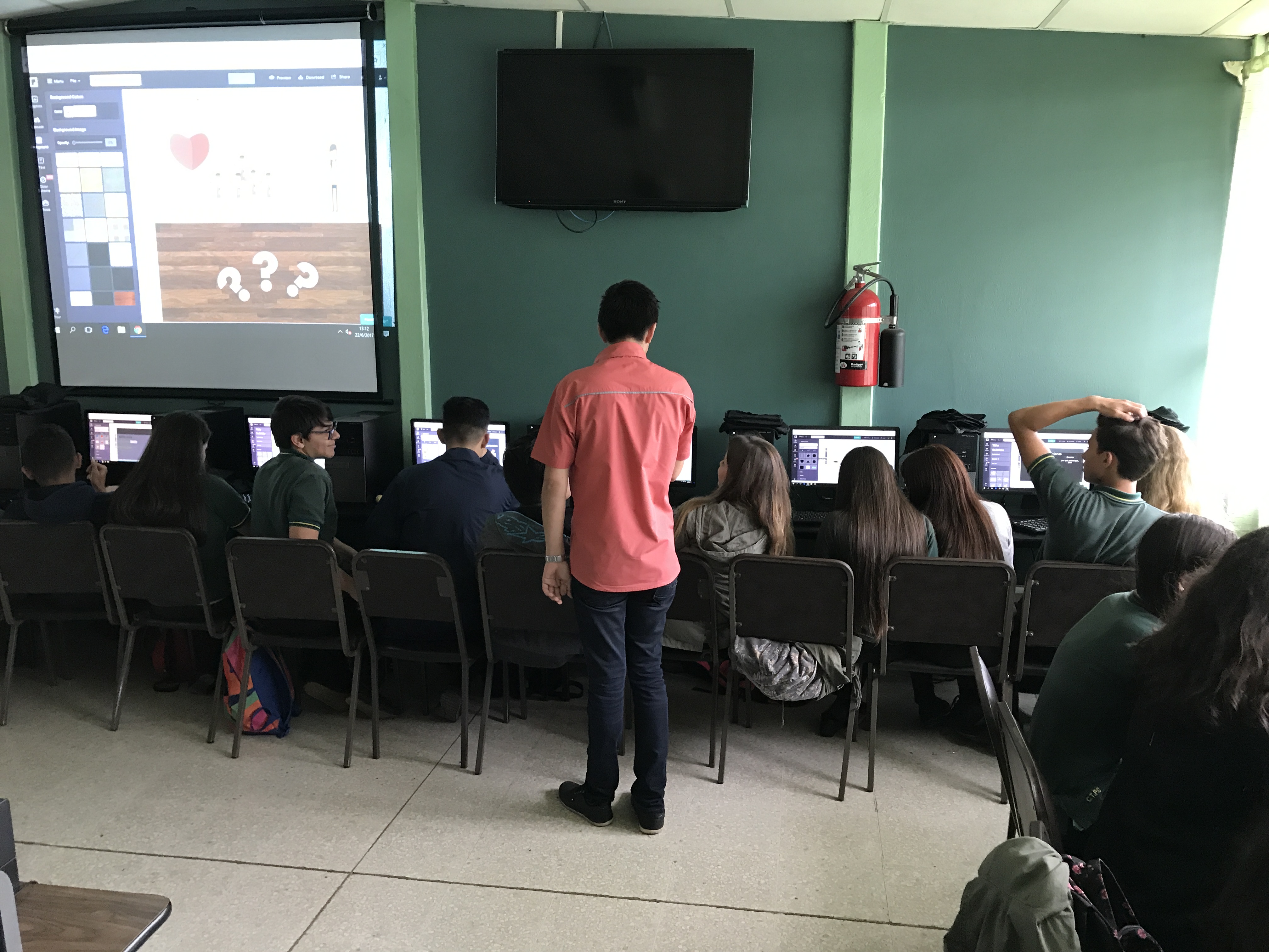 Profesor de Informática supervisando trabajo de estudiante