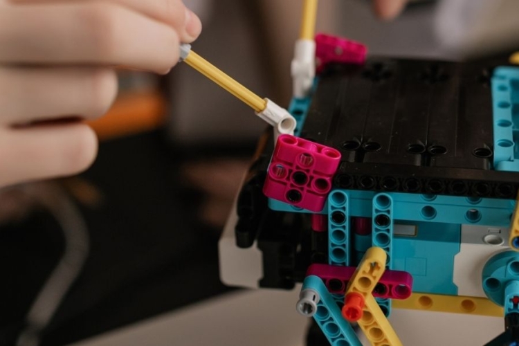 Manos armando un robot a base de legos.