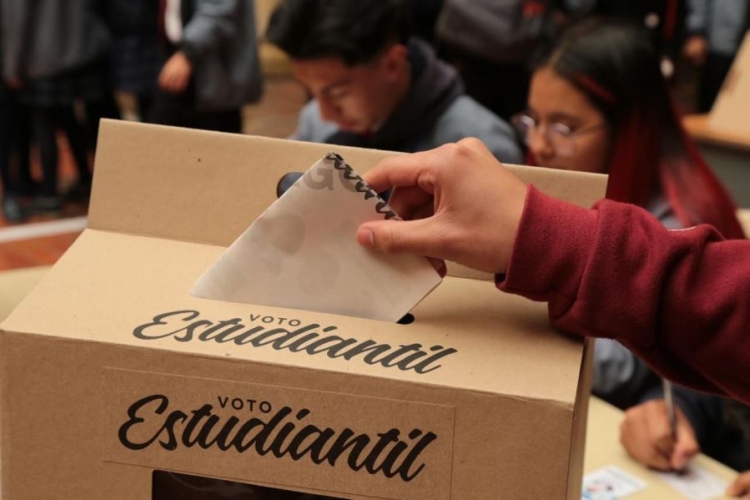 Persona estudiante depositando su voto en urna