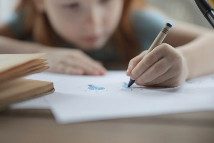 Una niña escribiendo con una crayola