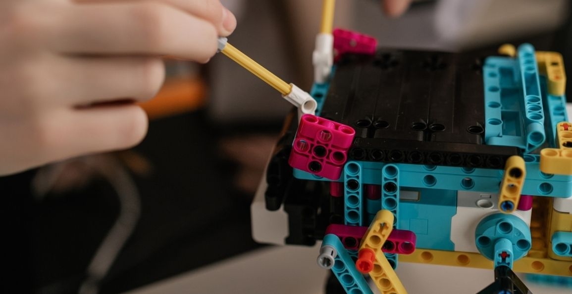 Manos armando un robot a base de legos.