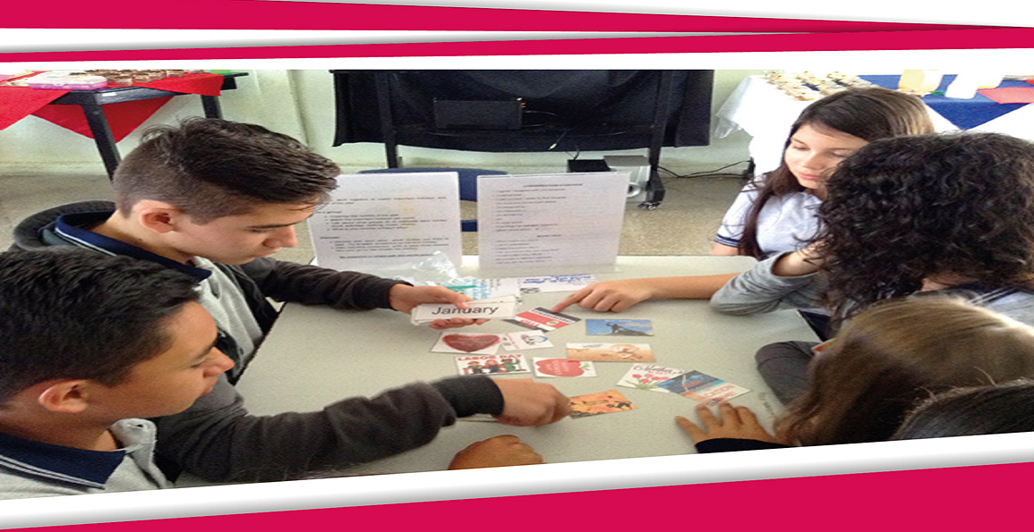 Estudiantes jugando con tarjetas alrededor de una mesa