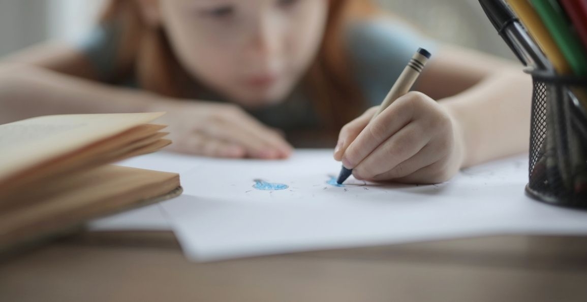 Una niña escribiendo con una crayola